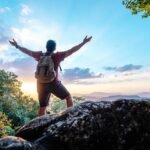 rear-view-back-young-asian-hiking-man-standing-riseup-hands-with-happy-peak-rocky-mountain-copy-space_1150-57186